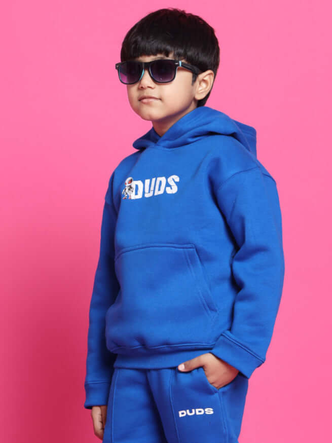 Boy wearing Spiderrobo oversized blue hoodie by DUDS against pink background