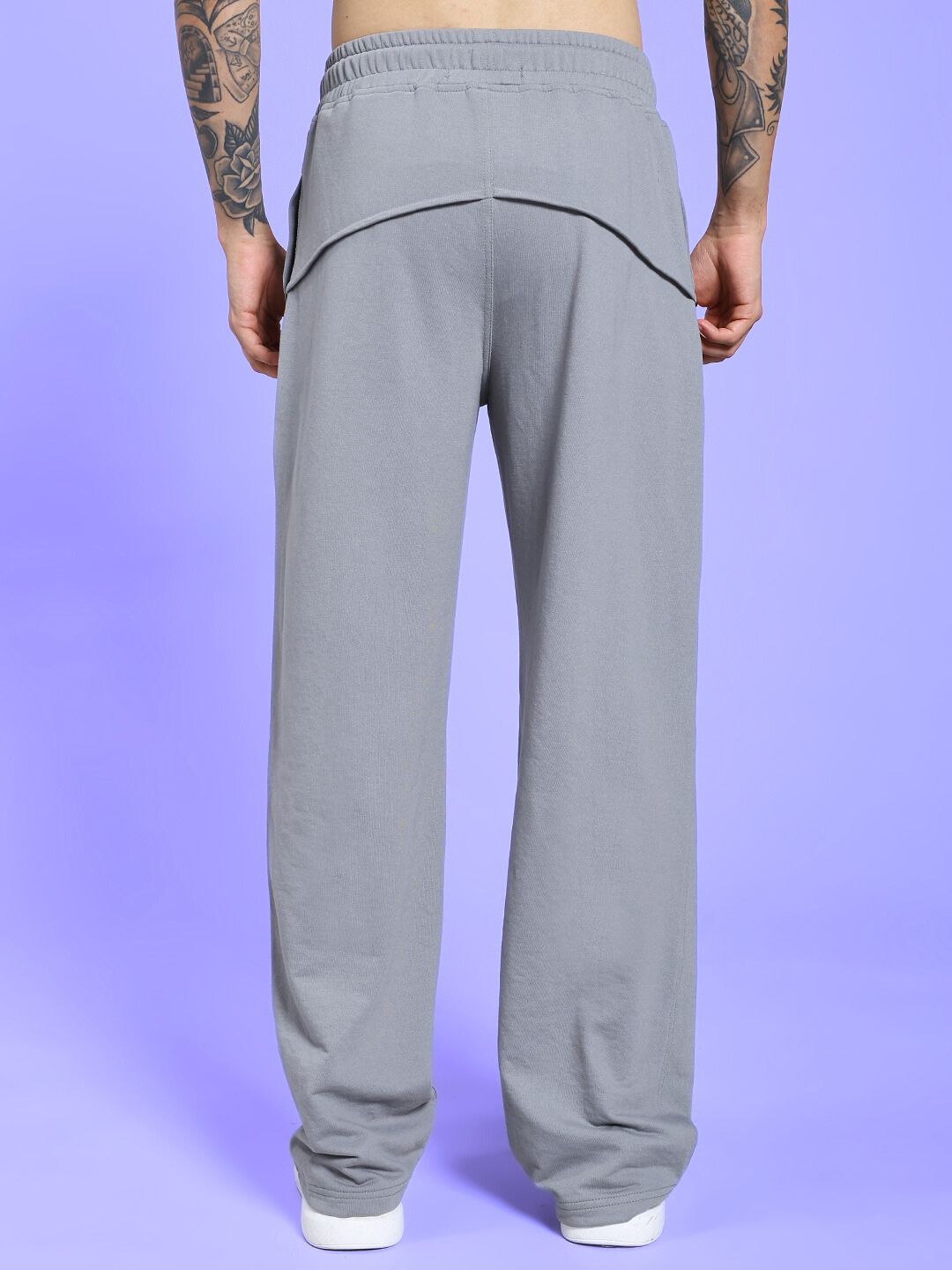 Back view of SPIRAL RELAXED-FIT JOGGERS GREY worn by model on purple background.