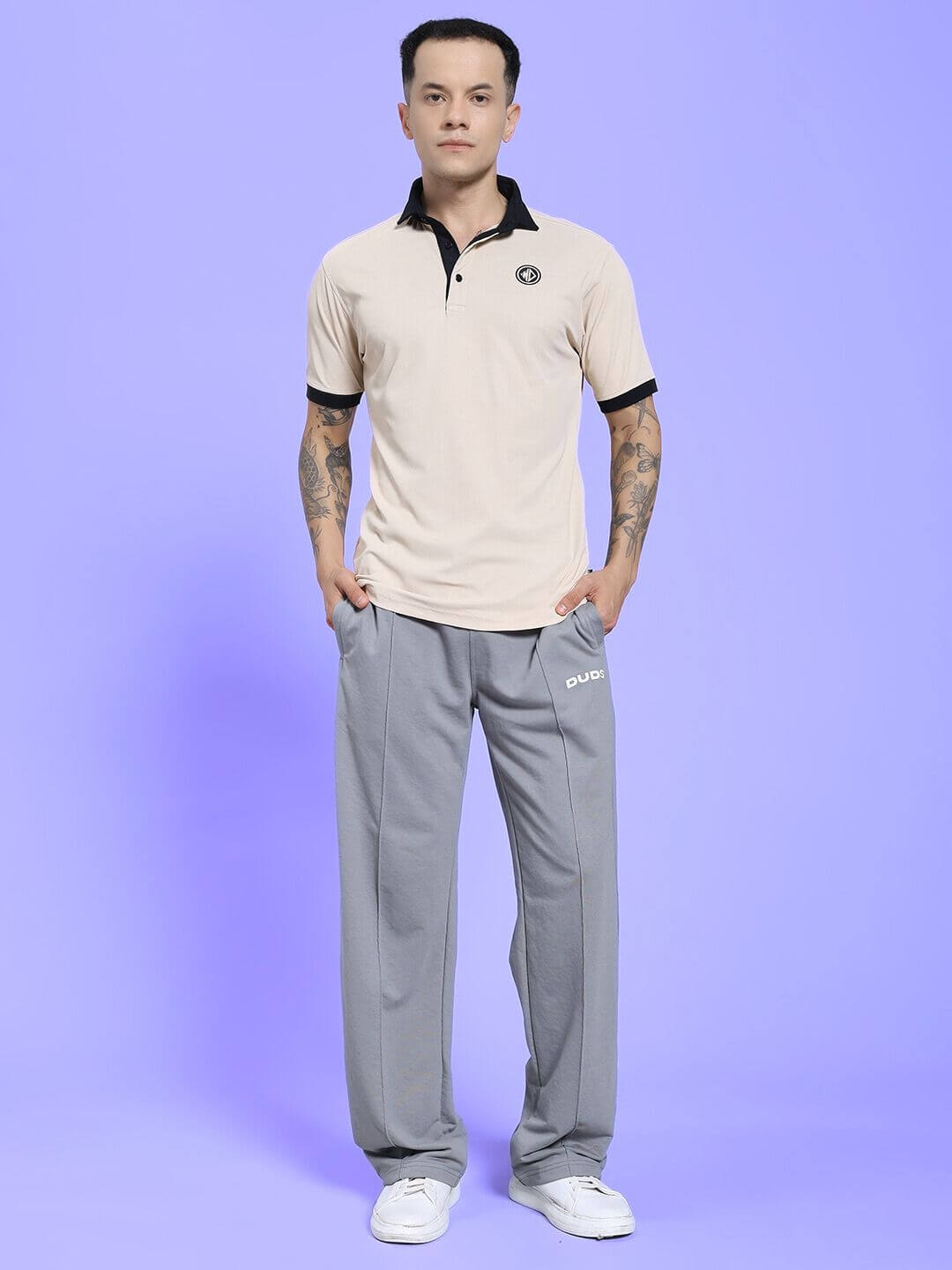 Man wearing SPIRAL RELAXED-FIT JOGGERS GREY standing against a light purple background