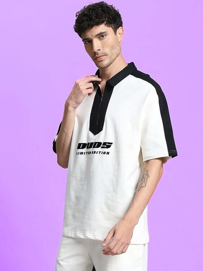 Man wearing SPLINTER OVER-SIZED T-SHIRT OFF WHITE with black trim, showcasing urban streetwear style against a purple background.