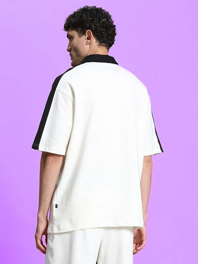 Man wearing SPLINTER OVER-SIZED T-SHIRT OFF WHITE, showcasing urban streetwear style against a purple background.