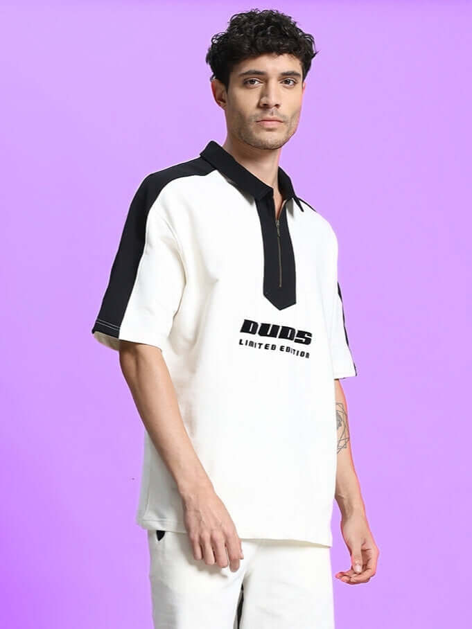 Model wearing SPLINTER OVER-SIZED T-SHIRT OFF WHITE, showcasing urban streetwear style in premium cotton against a purple background.