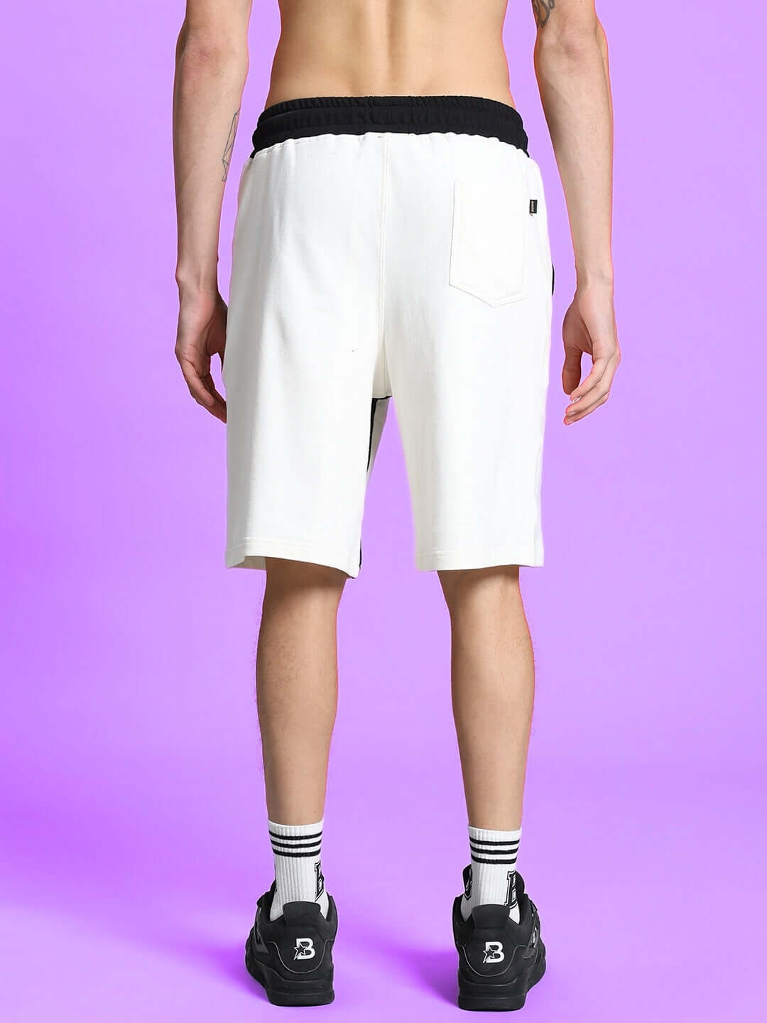 Back view of SPLINTER REGULAR FIT SHORTS OFF WHITE worn by a model against a purple background.