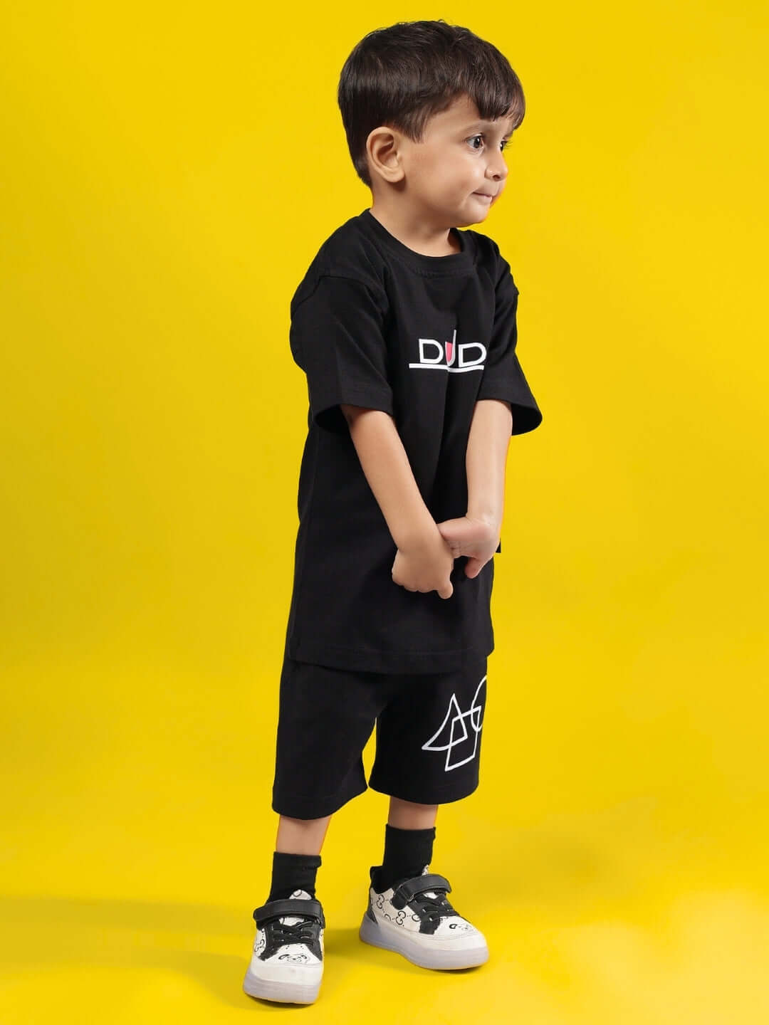 Child wearing SQUID BATTLE CO-ORD FOR BOYS & GIRLS BLACK by DUDS, featuring custom fit options, with yellow background.
