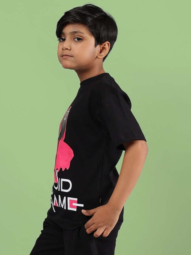 Boy wearing a black Squid Game T-shirt with pink and white design, ideal for boys and girls. Made to order by DUDS Tailors.