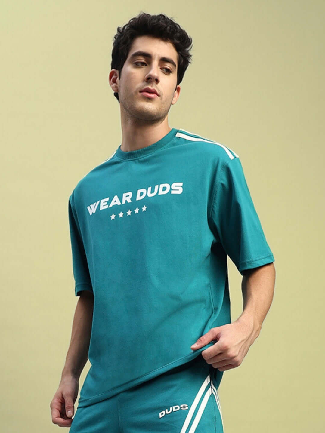 Model wearing STAR JUMPER OVER-SIZED T-SHIRT TEAL in breathable cotton, showcasing streetwear style for men and women.