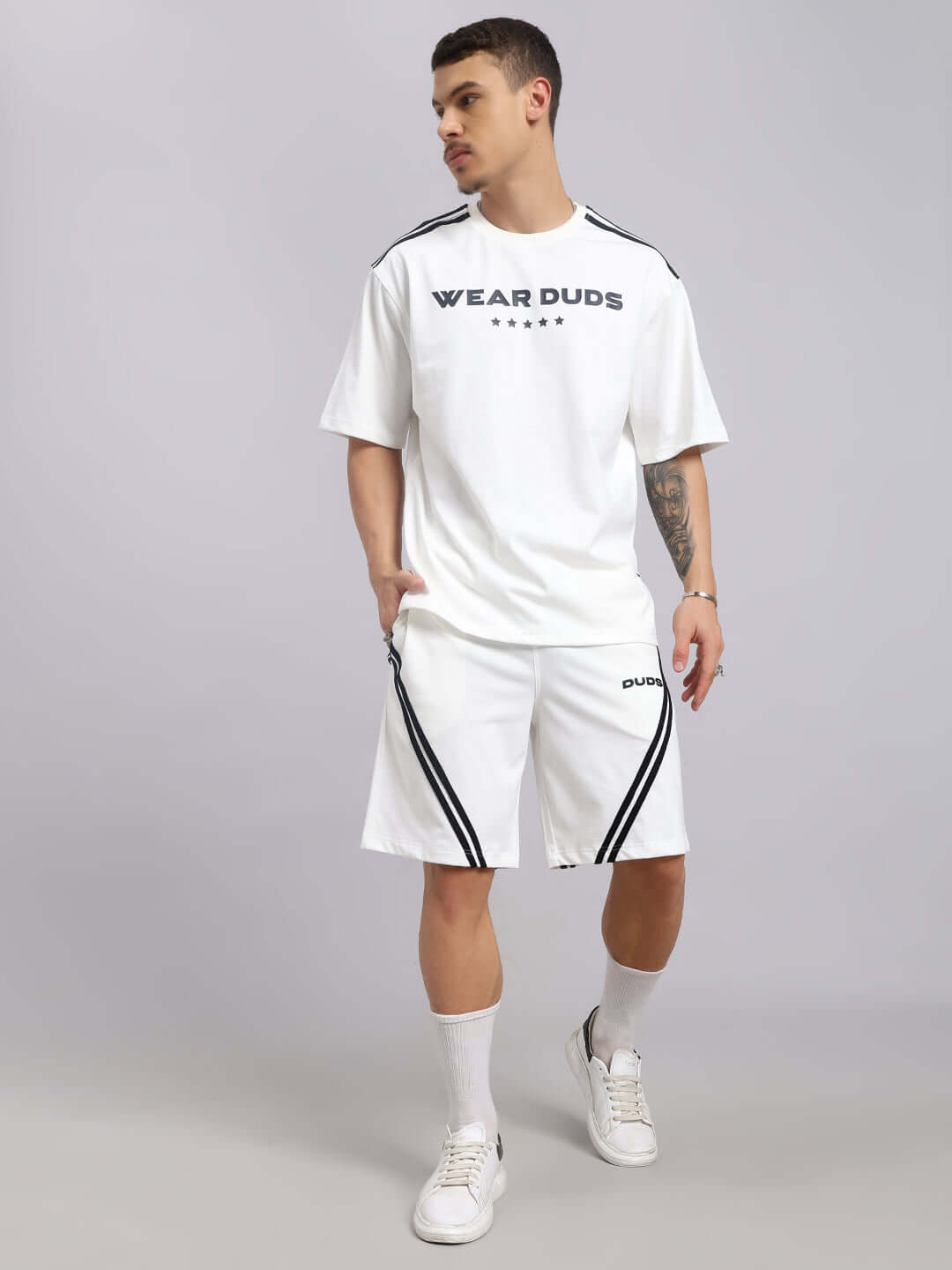 Man wearing casual outfit featuring STAR JUMPER REGULAR FIT SHORTS OFF WHITE with a matching white top in a stylish pose.
