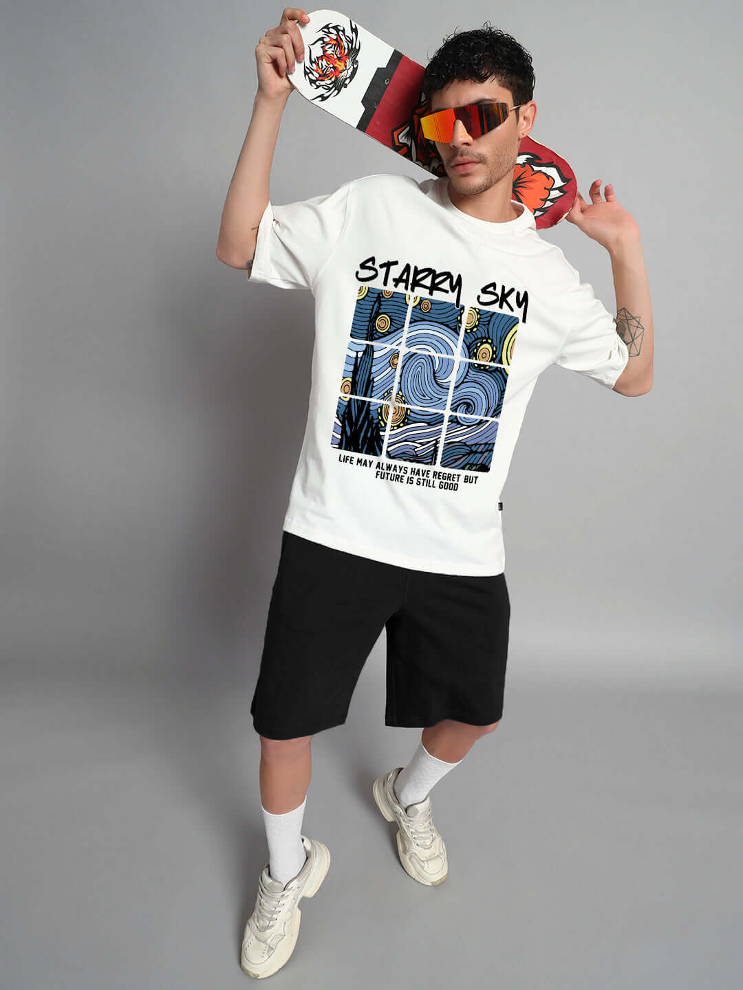 Model wearing Starry Sky Oversized T-Shirt in off-white, featuring celestial graphic, paired with black shorts and sneakers.