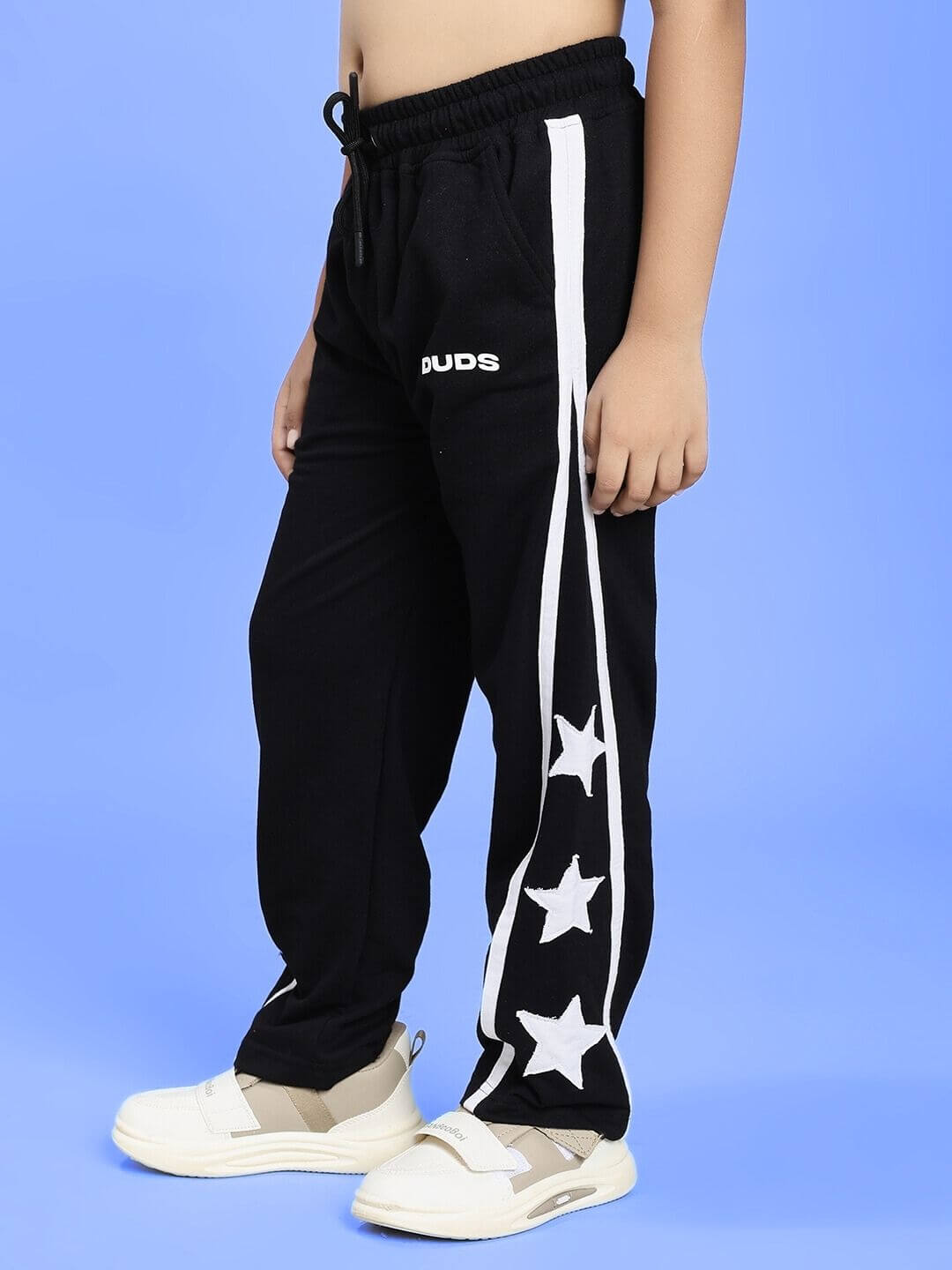 Boy wearing STELLAR RELAXEDFIT JOGGER FOR BOYS AND GIRLS BLACK with white stars design on blue background.