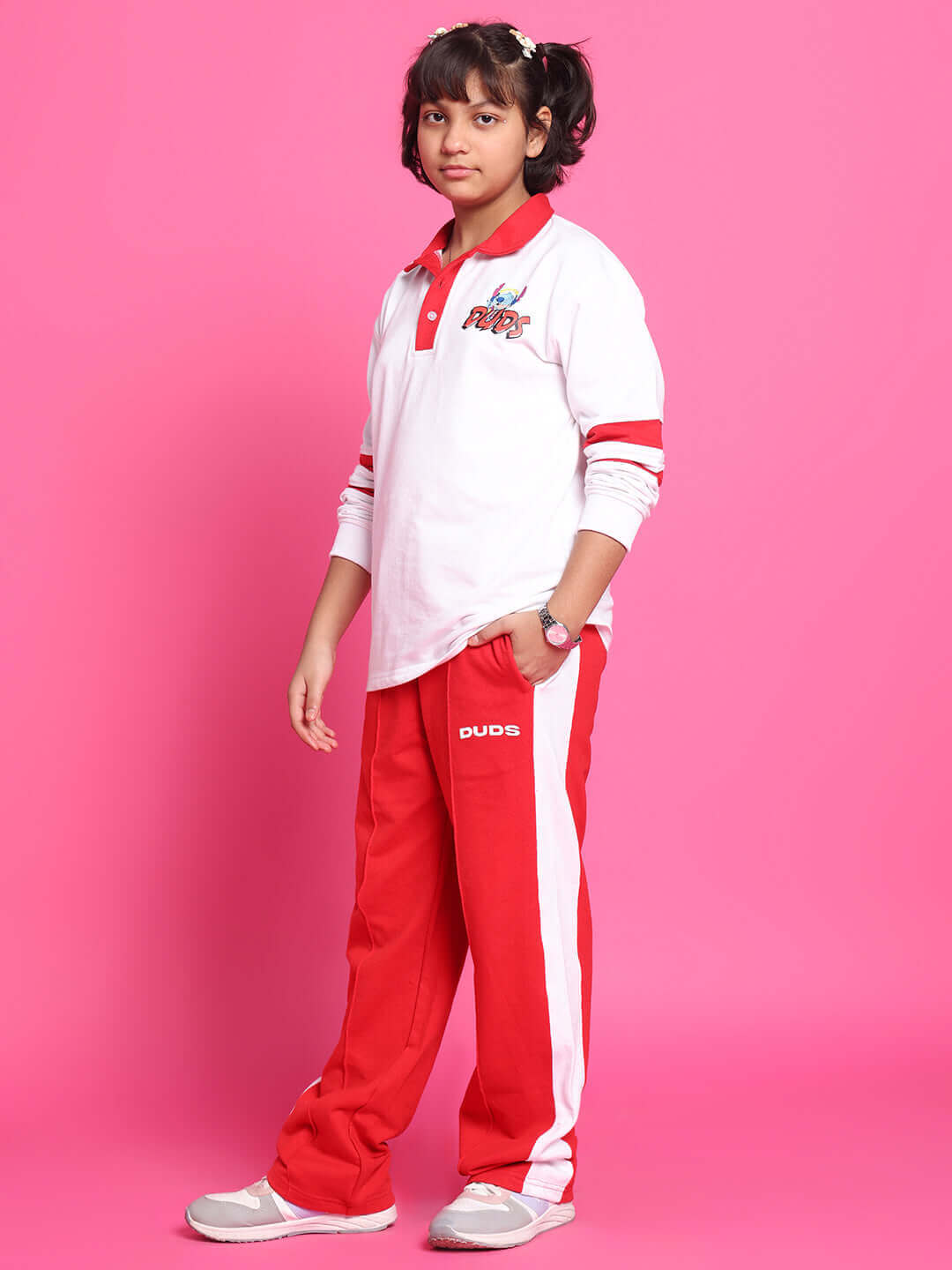 Child wearing STITCH OVERSIZED CO-ORD SET FOR BOYS GIRLS WHITE RED, featuring a white sweatshirt and red joggers against a pink background.