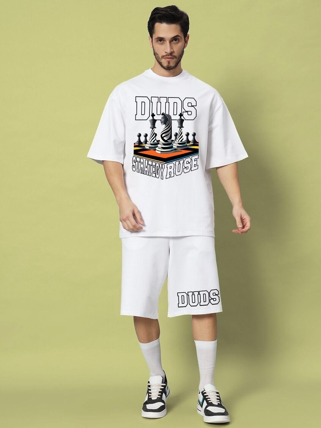 Man wearing STRATEGY RUSE CO-ORD SET WHITE with graphic design, displaying stylish lettering and colorful details.