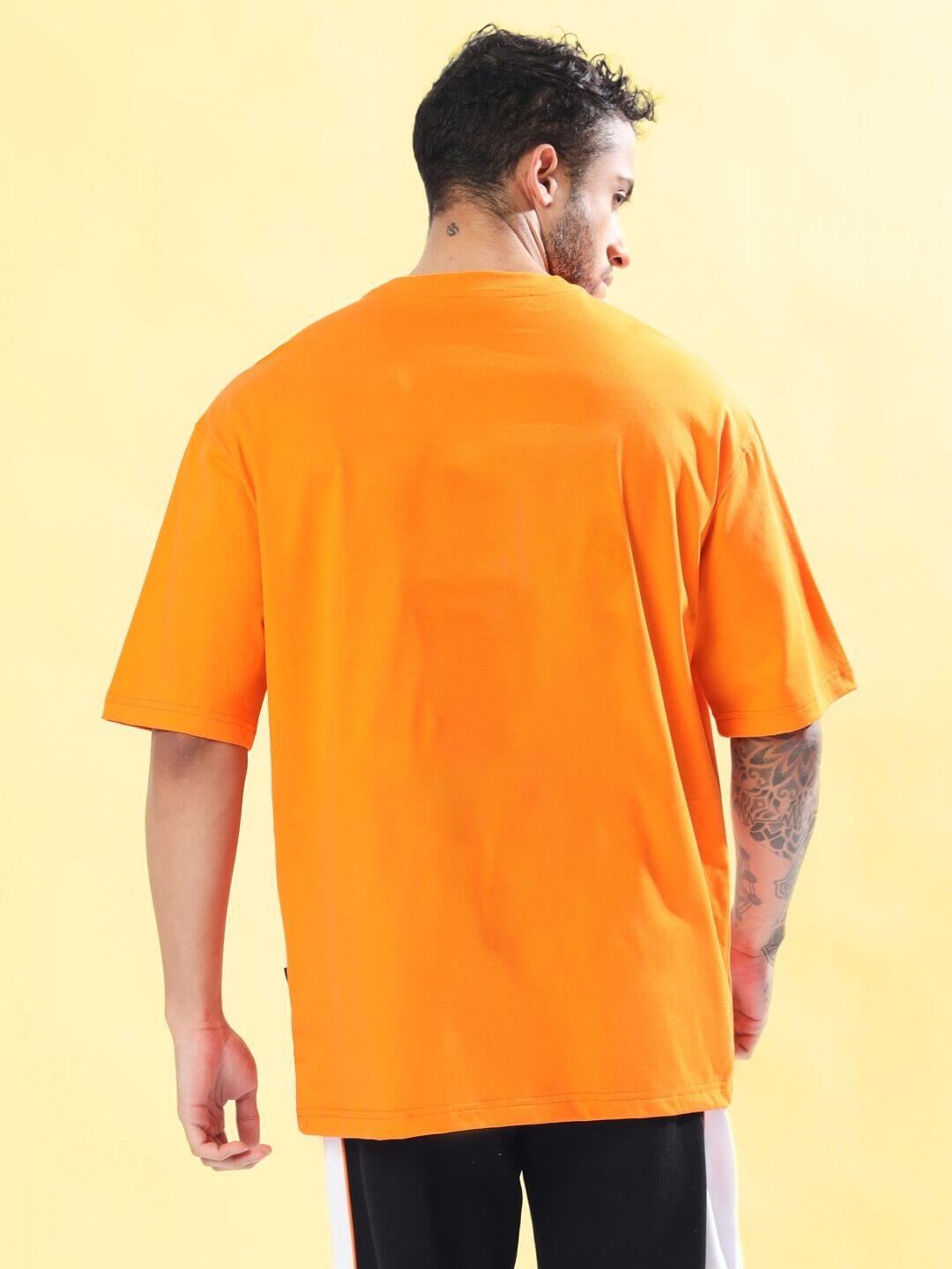 Back view of a model wearing STRATEGY RUSE OVER-SIZED T-SHIRT ORANGE, showcasing the vibrant color and comfortable fit.