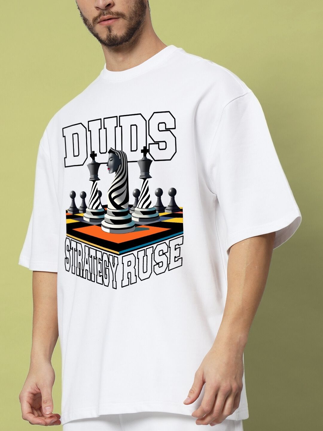 Man wearing STRATEGY RUSE OVER-SIZED T-SHIRT WHITE with chess design on a light green background