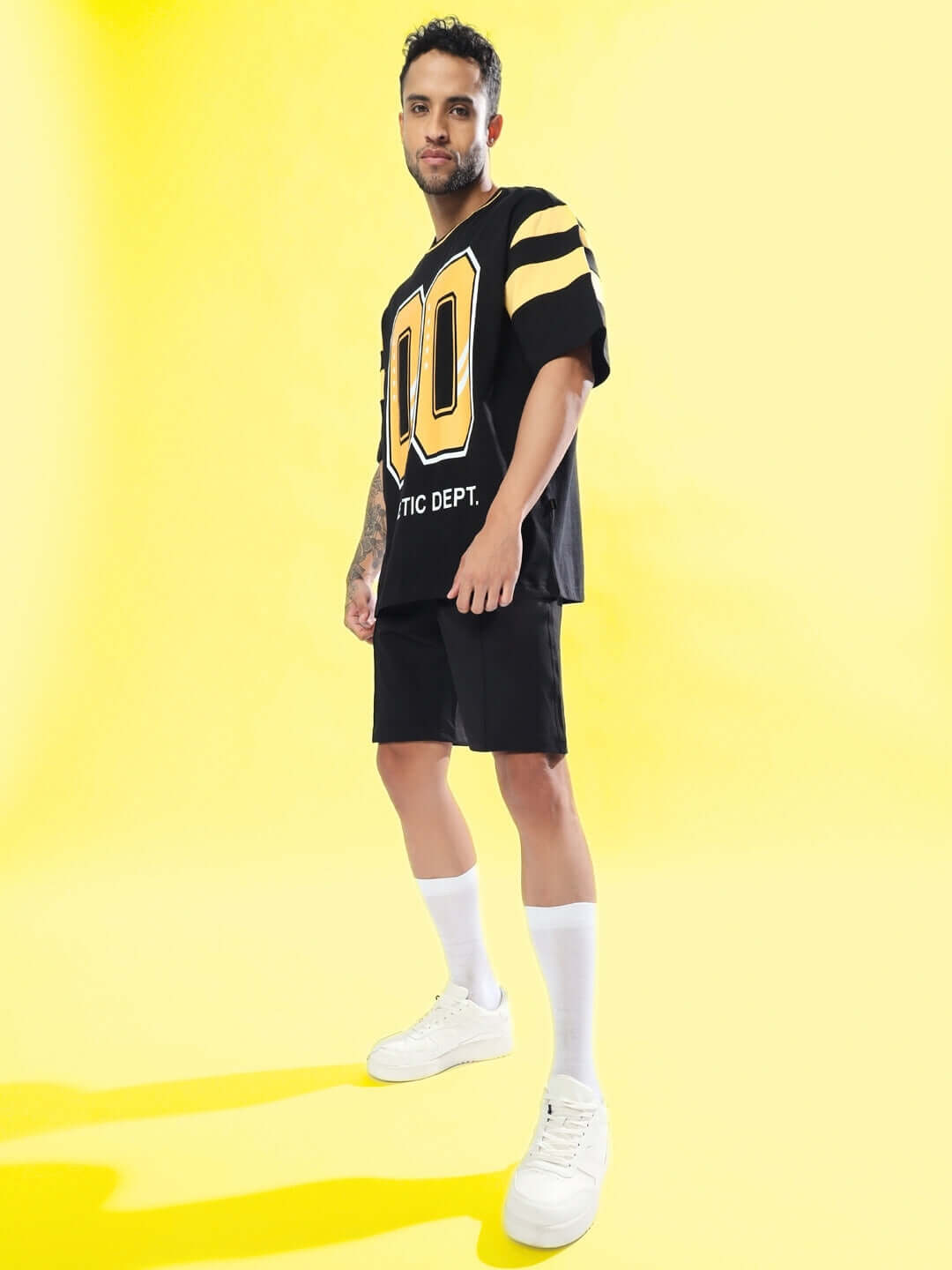 Model wearing black sturdy front plated shorts with custom fit option available, standing on a yellow background.