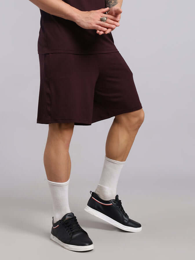 Model wearing STRENGTH FREAK SHORTS in wine color, showcasing casual athletic style and comfort fit.