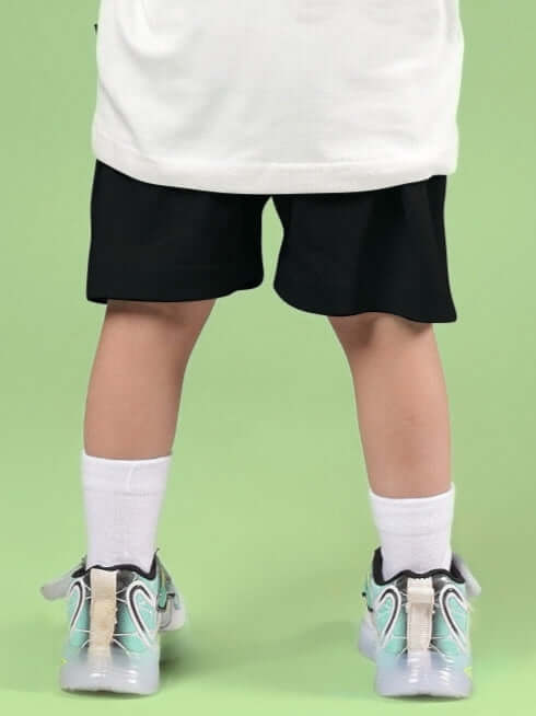Back view of child wearing STYLISH ROBOT SHORTS FOR BOYS & GIRLS BLACK against green background.