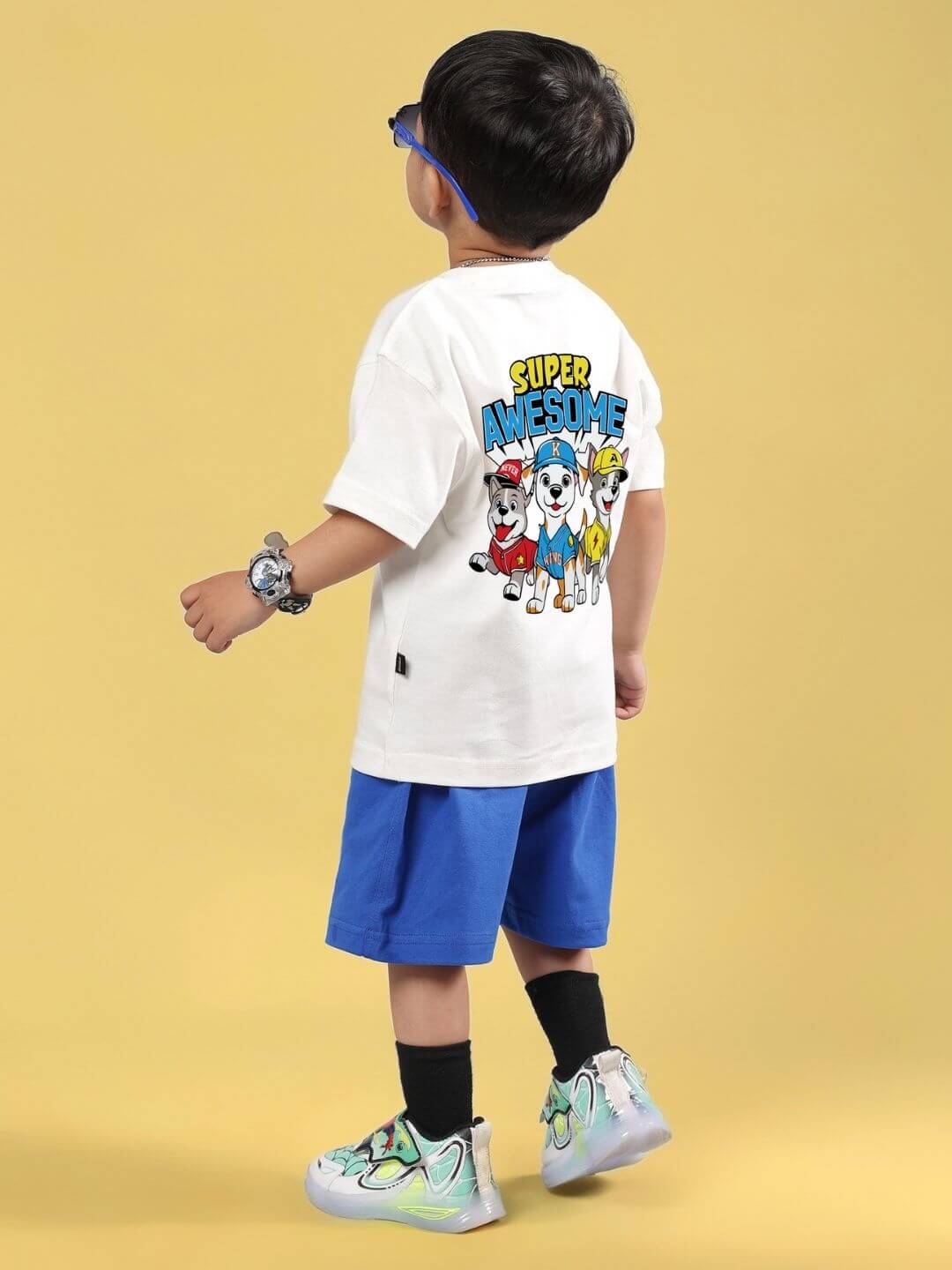 Child wearing SUPER AWESOME CO-ORD FOR BOYS AND GIRLS OFF WHITE ROYAL BLUE set, featuring a graphic white shirt and blue shorts.