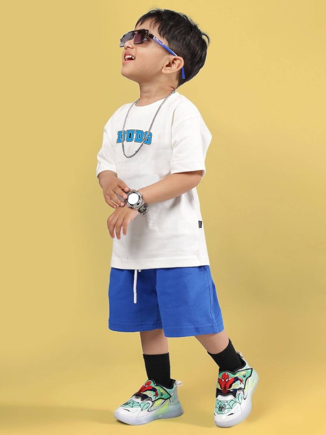 Child wearing SUPER AWESOME CO-ORD FOR BOYS AND GIRLS OFF WHITE ROYAL BLUE, stylish kids' outfit with sunglasses and sneakers.