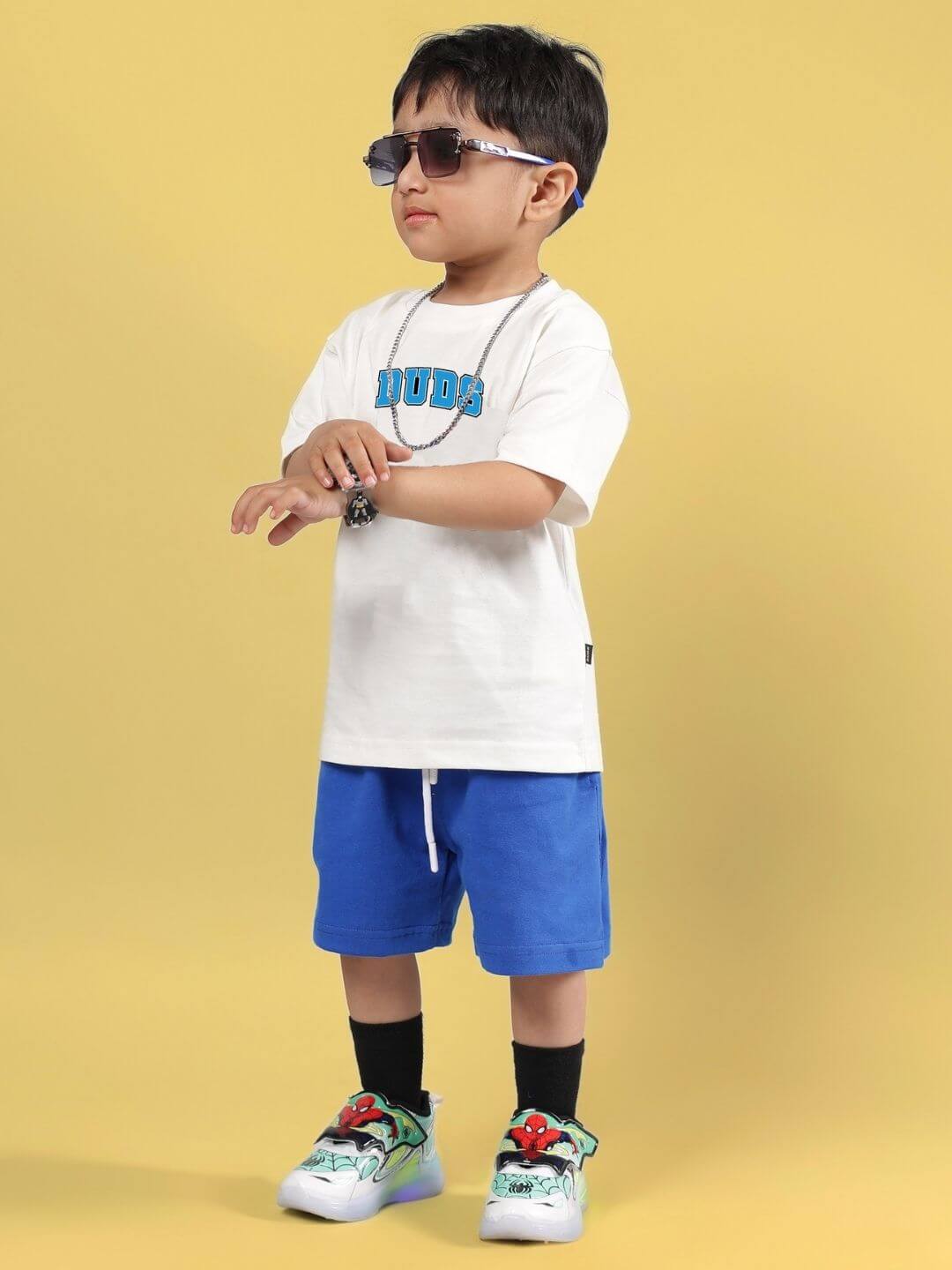 Child wearing SUPER AWESOME CO-ORD FOR BOYS AND GIRLS OFF WHITE ROYAL BLUE with sunglasses, showcasing trendy kids' fashion.