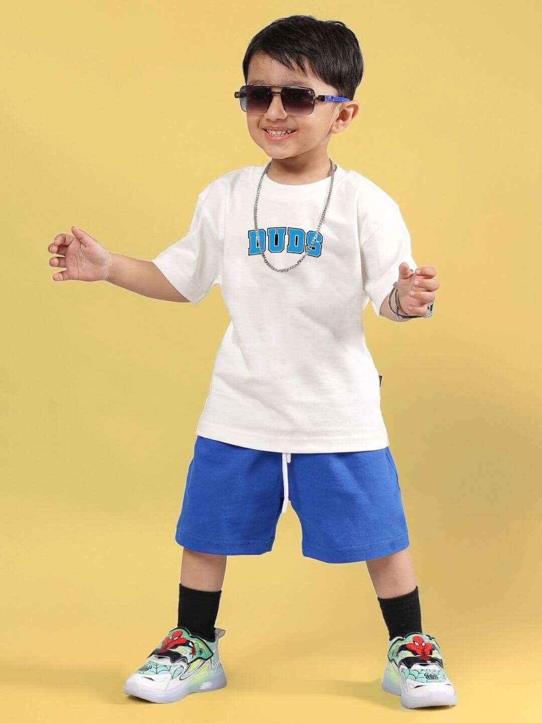 Kid wearing SUPER AWESOME CO-ORD FOR BOYS AND GIRLS OFF WHITE ROYAL BLUE set, smiling, standing on a yellow background.