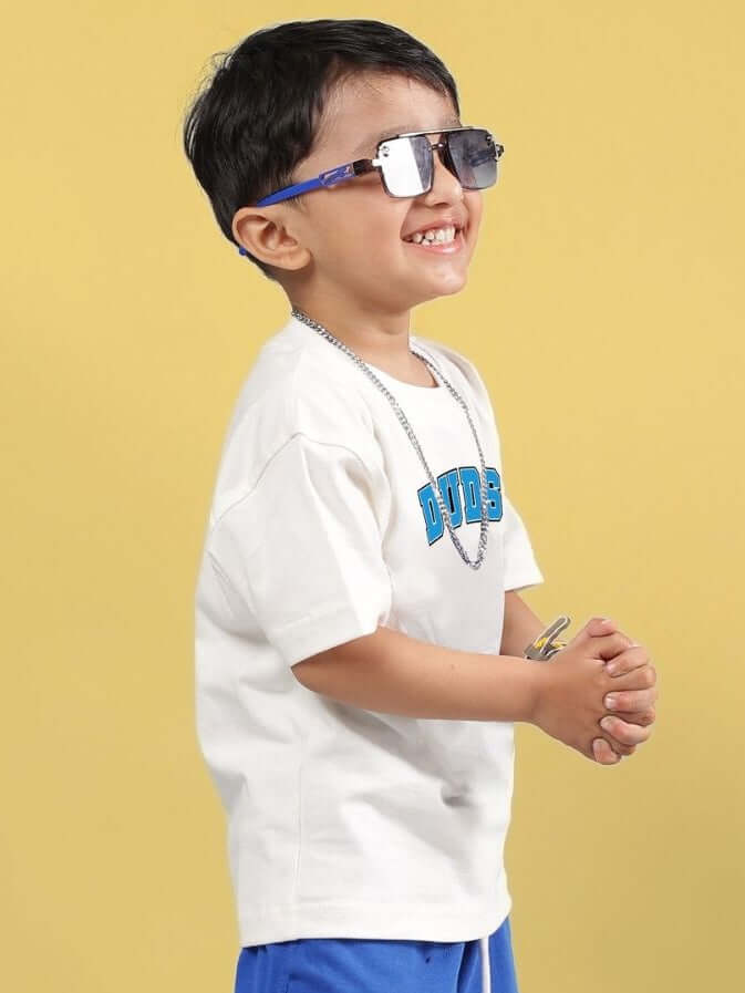 Child wearing SUPER AWESOME T-SHIRT FOR BOYS AND GIRLS OFF WHITE with sunglasses, standing against a yellow background.