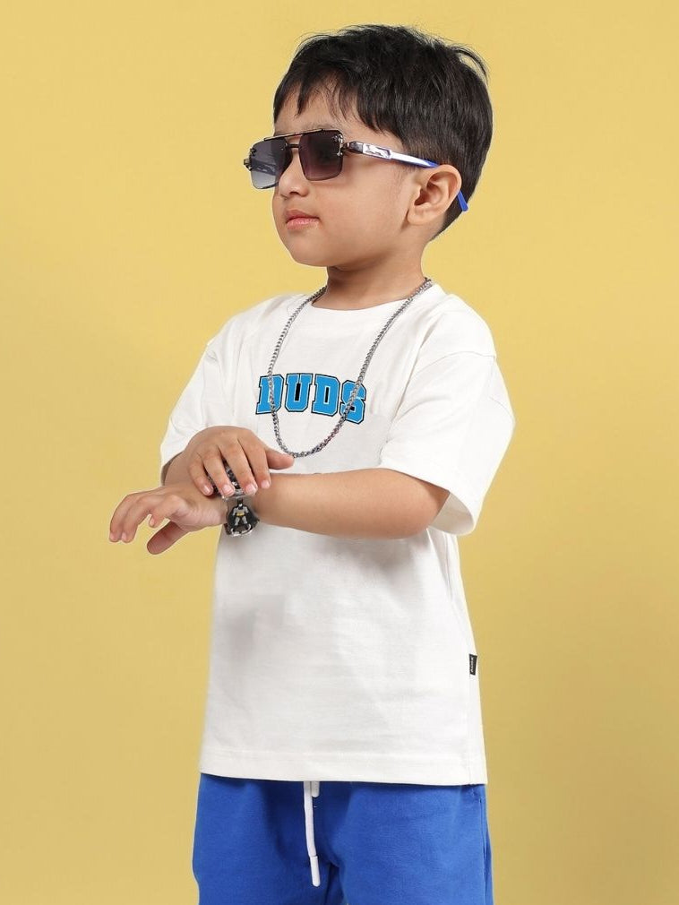 Child wearing SUPER AWESOME T-SHIRT FOR BOYS AND GIRLS OFF WHITE, styled with sunglasses and a necklace, standing against a yellow background.