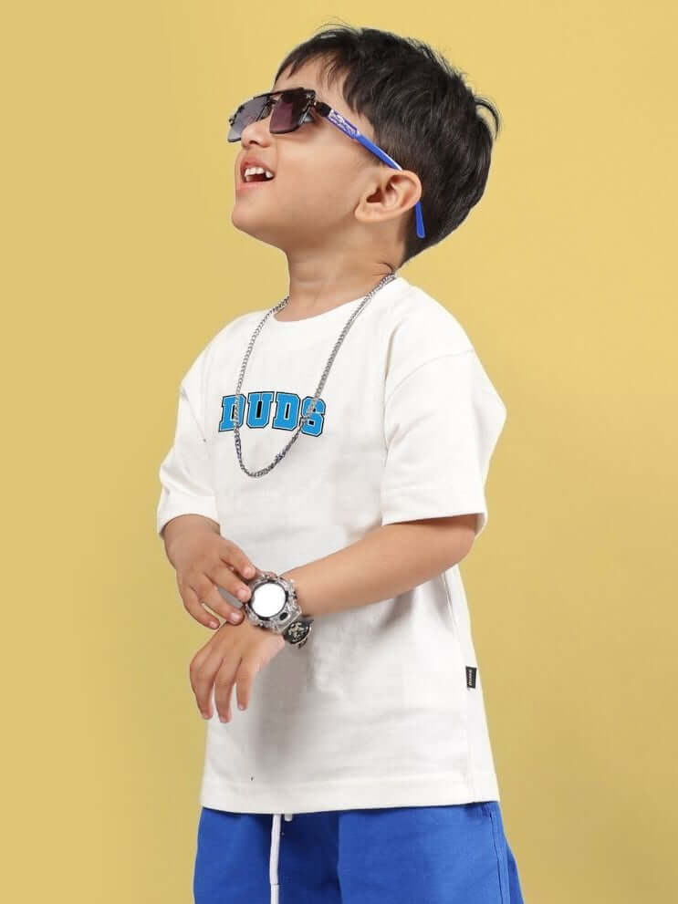 Child wearing SUPER AWESOME T-SHIRT FOR BOYS AND GIRLS OFF WHITE, sunglasses, and blue shorts, showcasing casual style.