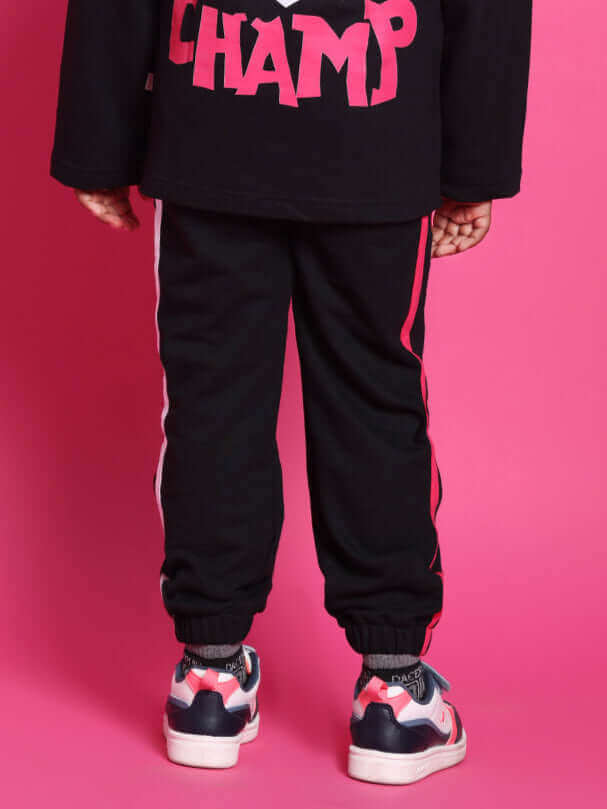 Child wearing black SUPER CHAMP co-ord outfit with pink lettering, designed for boys and girls, crafted from premium cotton and elastane.