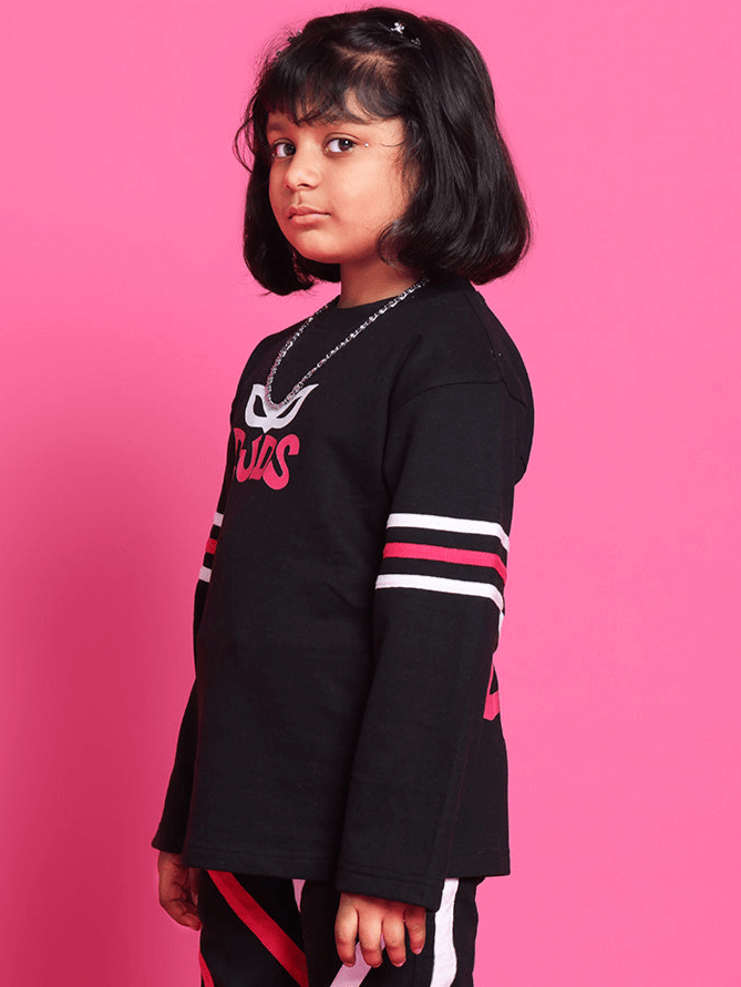 Child wearing SUPER CHAMP OVER-SIZED SWEATSHIRT FOR BOYS GIRLS BLACK with vibrant pink background.