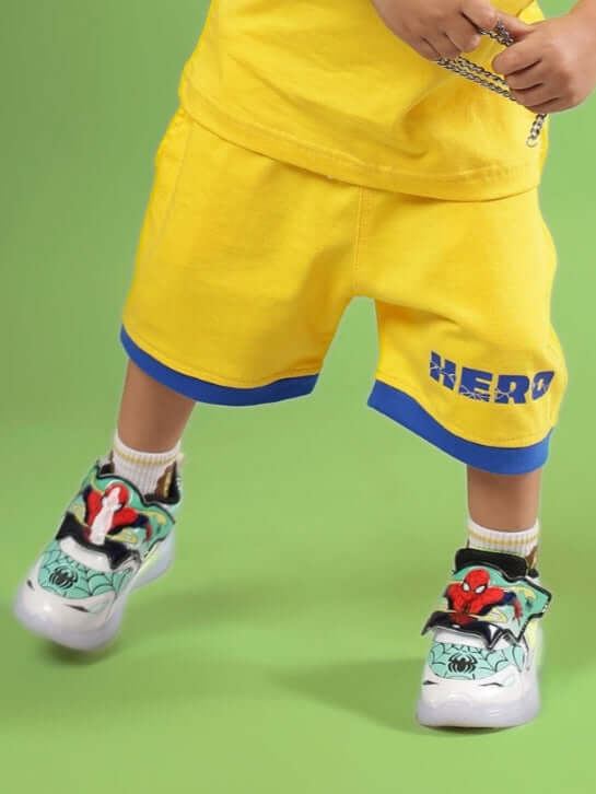 SUPER HERO SHORTS FOR BOYS & GIRLS YELLOW with blue trim, child wearing vibrant shoes.