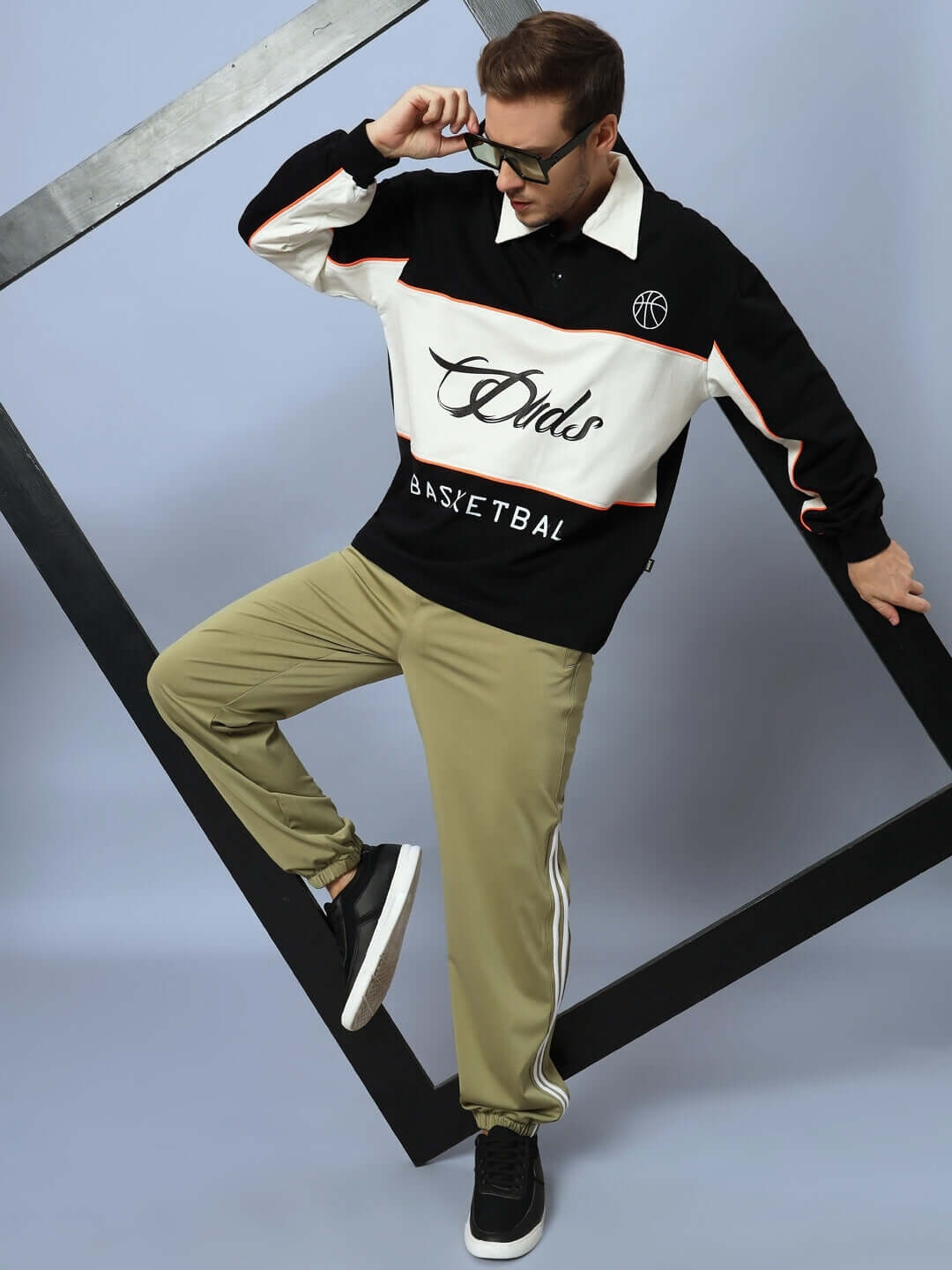 Model wearing olive green relaxed pant jogger from DUDS, styled with a black and white sweatshirt. Made-to-order tailoring, custom fit available.