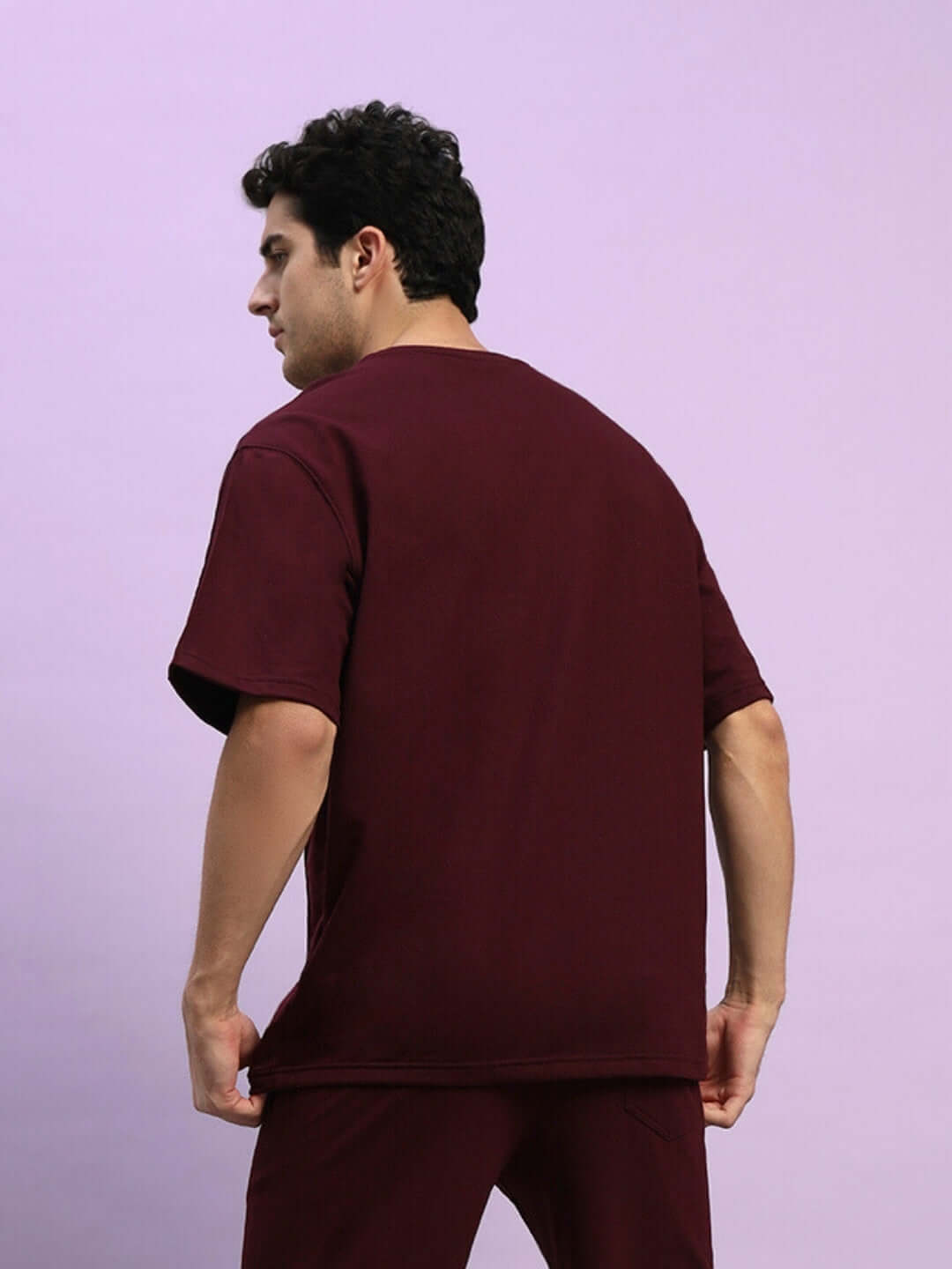 Back view of model wearing SUPERIOR OVER SIZED T-SHIRT MAROON, made of premium heavy gauge fabric, 97% cotton, 3% elastane.