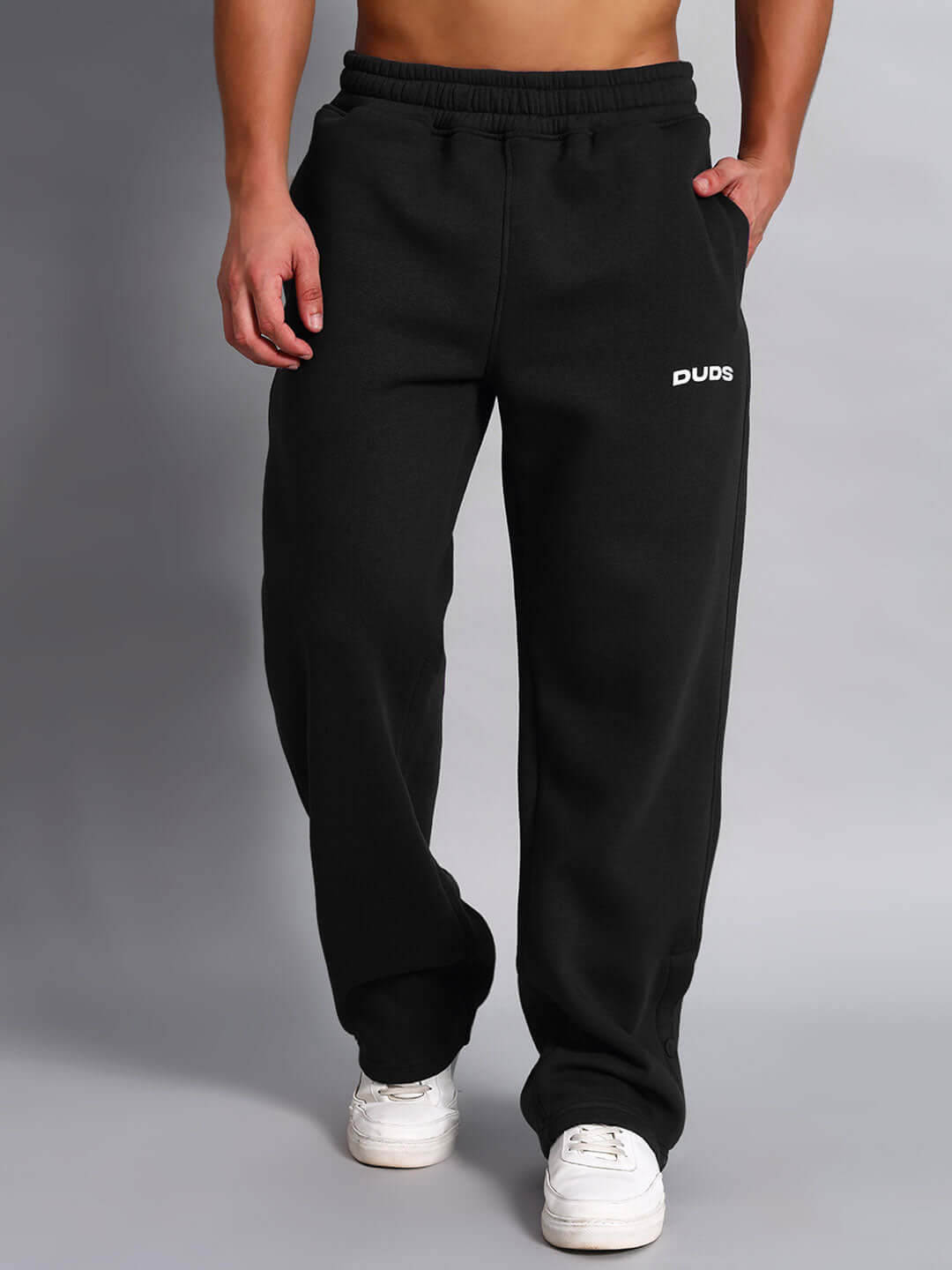 Person wearing WEARDUDS SUPREME FLEECE CO-ORD BLACK pants with logo, front view, casual wear.