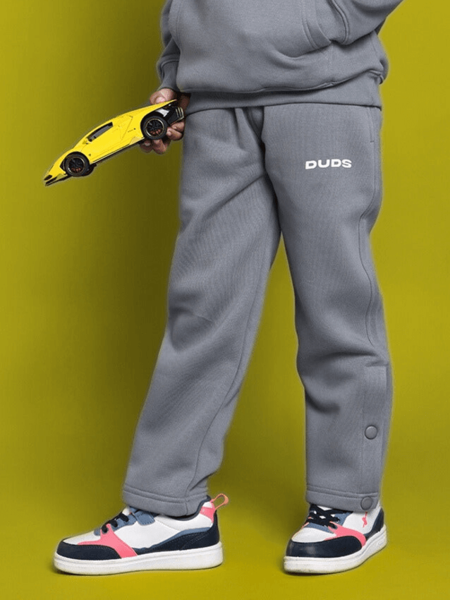 Child wearing grey Tabby Fleece Pants holding toy car, showcasing comfortable and stylish clothing for boys and girls.