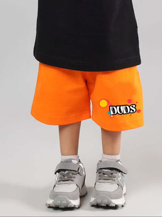 Child wearing bright orange 'Take the Step' shorts from DUDS, designed for boys and girls. Casual trendy fashion for kids.