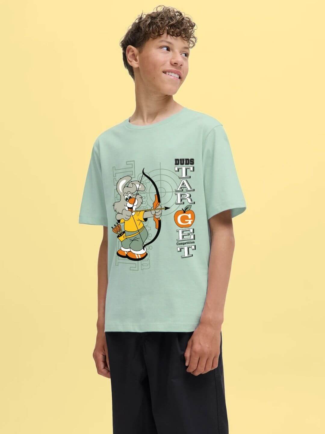 Boy wearing TARGET PRINTED T-SHIRT FOR BOYS AND GIRLS LIGHT GREEN with target print on yellow background