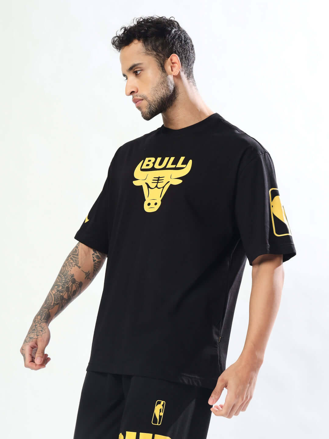 Model wearing TAURUS oversized black t-shirt with custom fit option from DUDS, showcasing bull logo in yellow.