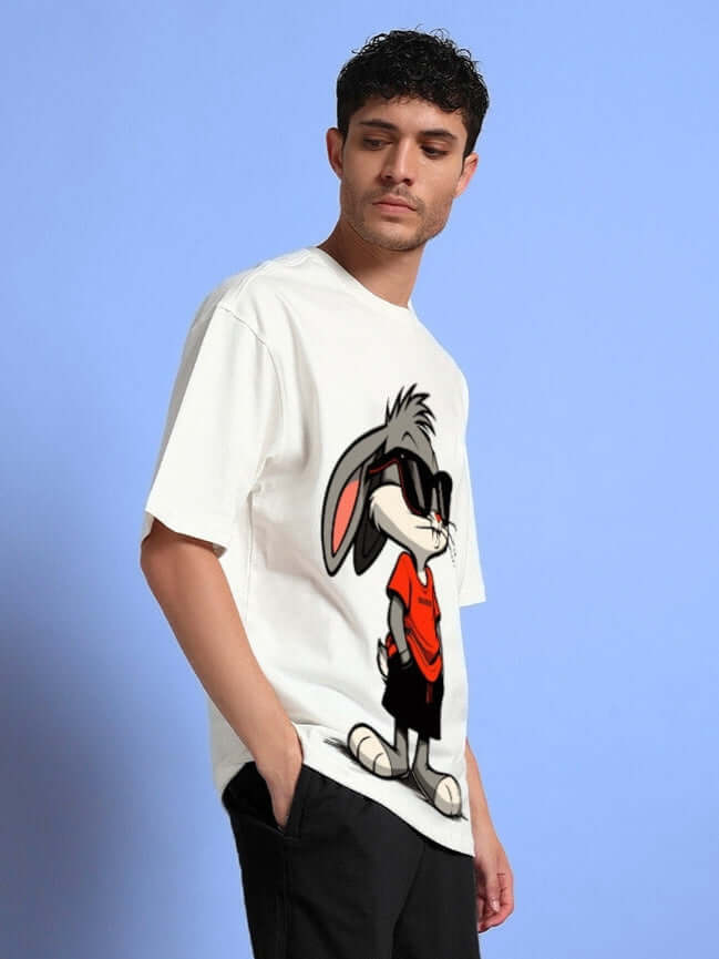 Man wearing THINK BIG BUNNY TOONS OVERSIZED T-SHIRT OFF WHITE with graphic design, showcasing trendy streetwear style.
