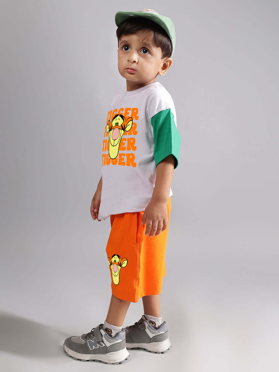 Young child wearing orange tiger-themed shorts by DUDS, paired with a matching t-shirt and grey sneakers.