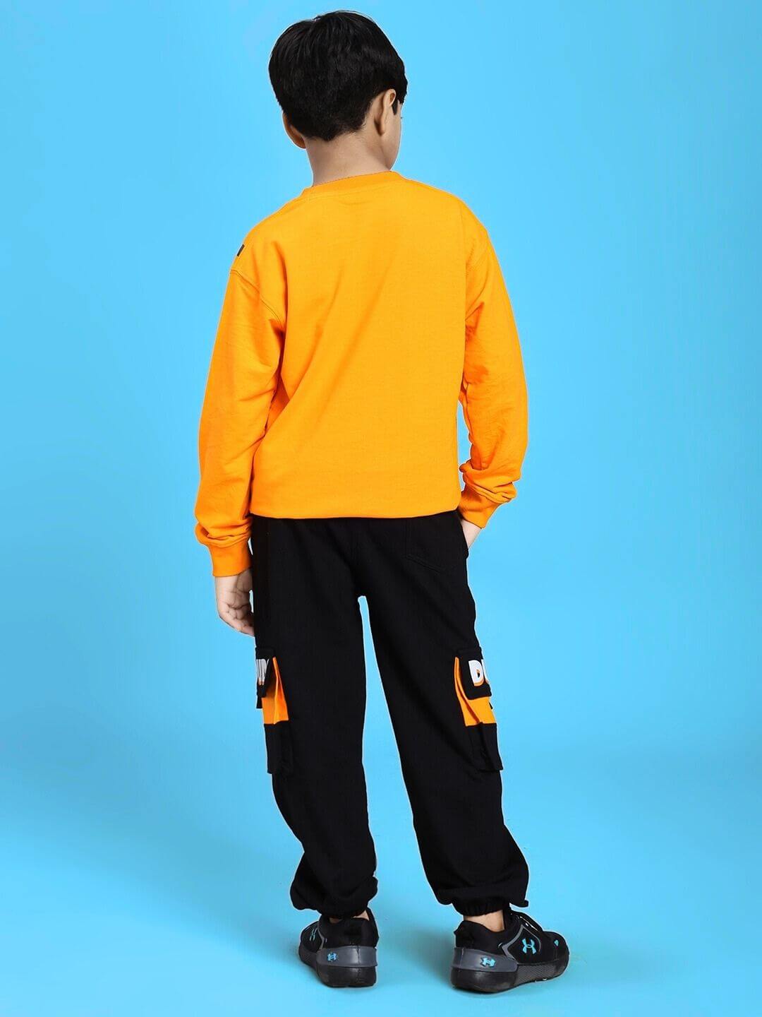 Child wearing TIGON KIDS CO-ORD SET FOR BOYS AND GIRLS ORANGE BLACK with orange top and black pants, standing against blue background.