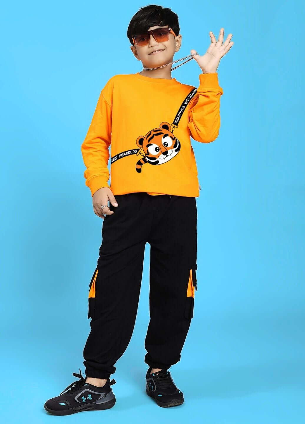 Child wearing TIGON KIDS CO-ORD SET FOR BOYS AND GIRLS ORANGE BLACK with a vibrant orange top and black pants on a blue background.