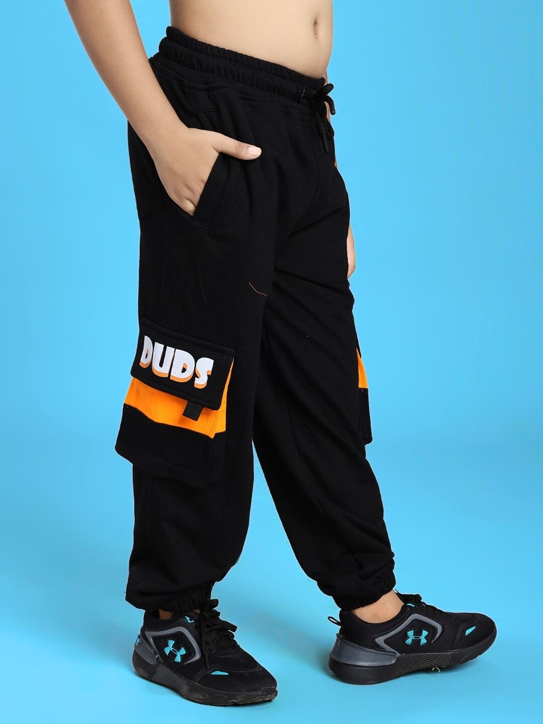 Child wearing TIGON KIDS JOGGER FOR BOYS AND GIRLS RED BLACK showcasing sporty design with black and orange accents on a blue background.