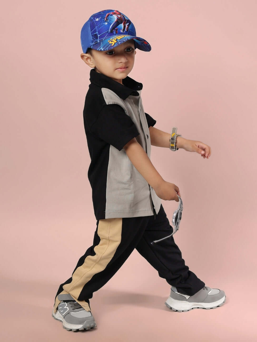 Child wearing TINGE CO-ORD FOR BOYS & GIRLS GREY BLACK with trendy outfit, walking confidently in a playful pose on a pink background.