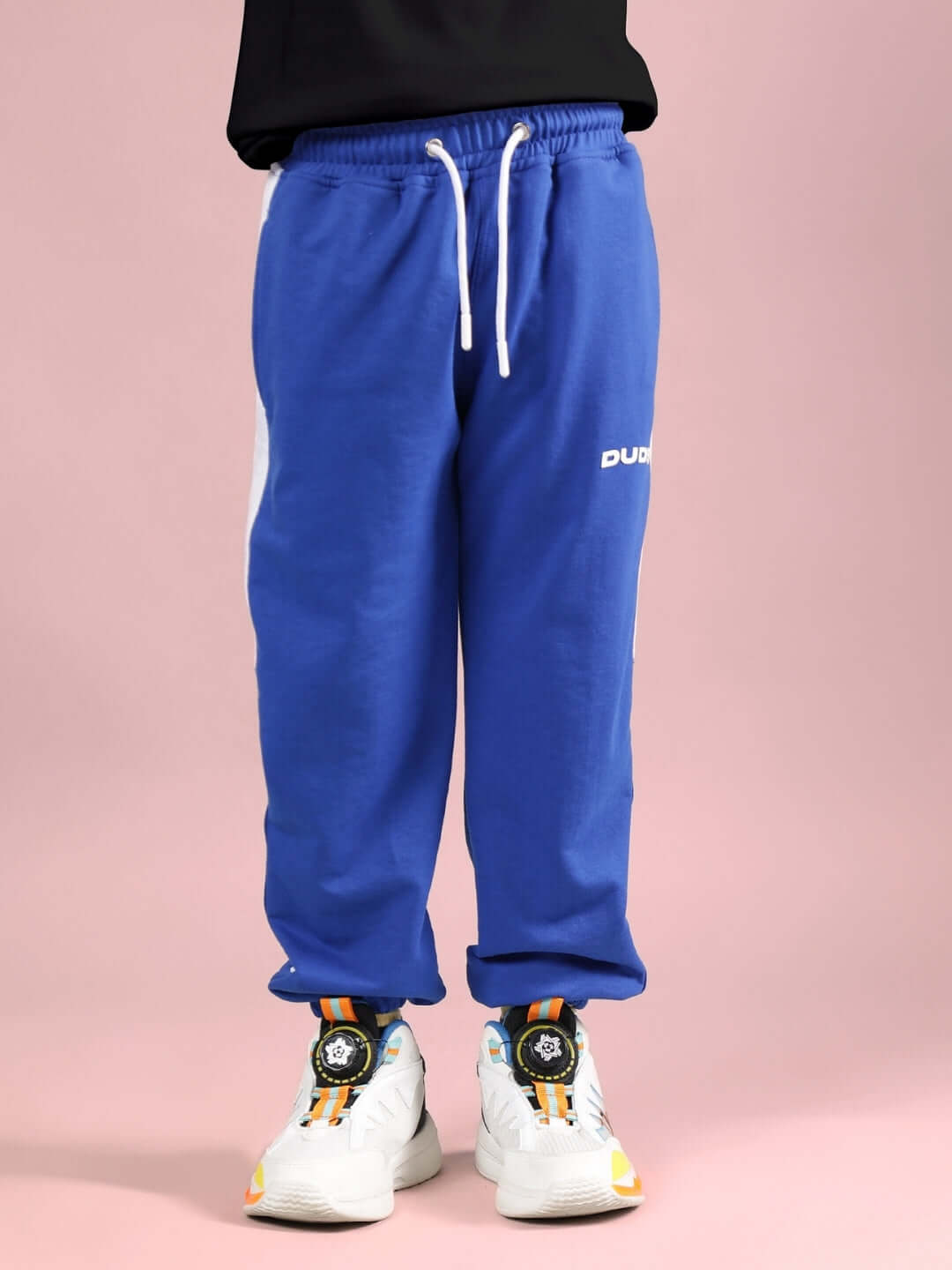 TINY TOON PRINTED CO-ORD FOR BOYS & GIRLS BLACK-R BLUE pants displayed with sneakers, highlighting the custom fit option for personalized sizing.