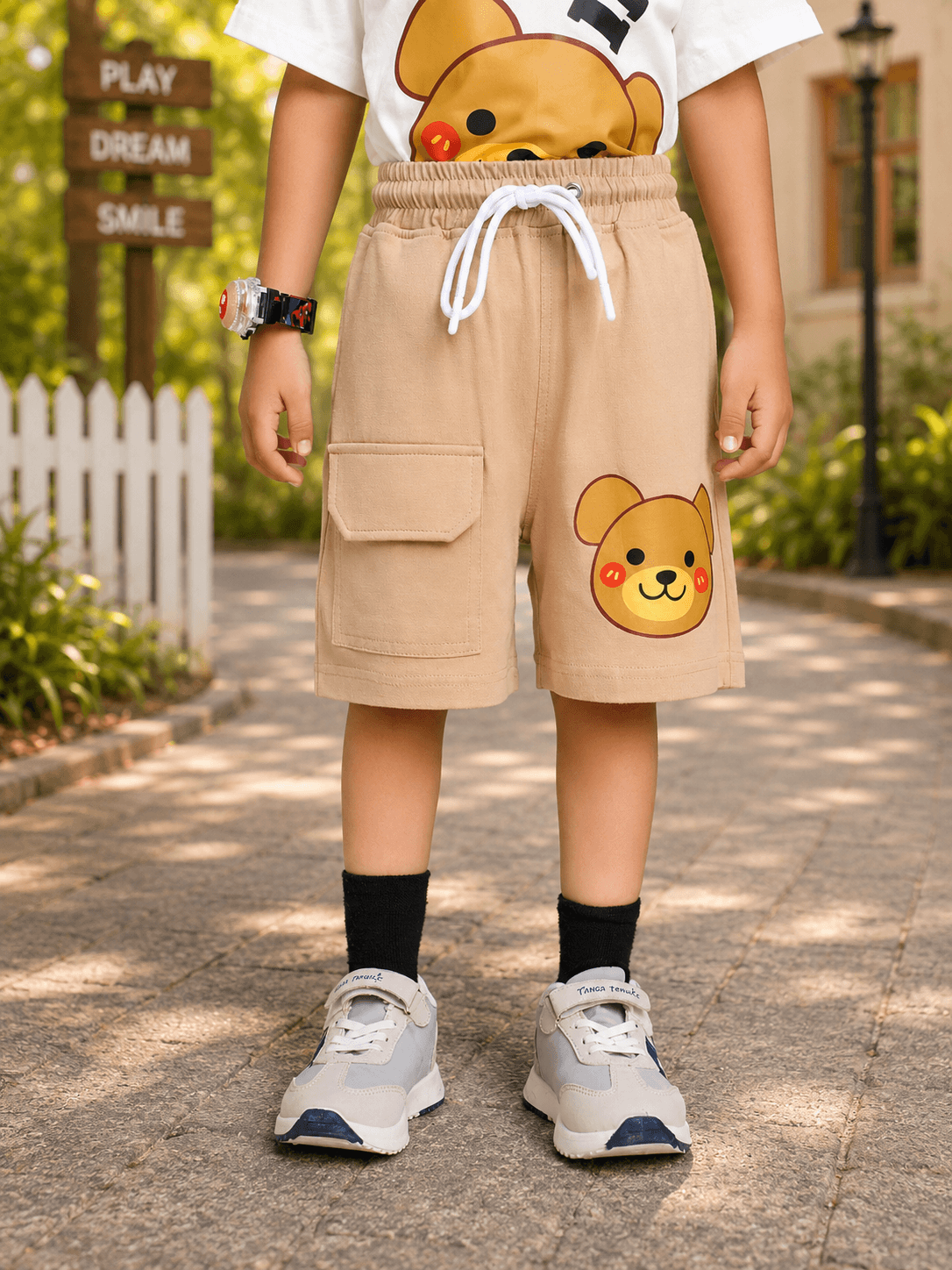 TINY TREND BEAR COOL SHORTS FOR BOYS GIRLS BEIGE worn by a child outdoors, featuring a cute bear design.