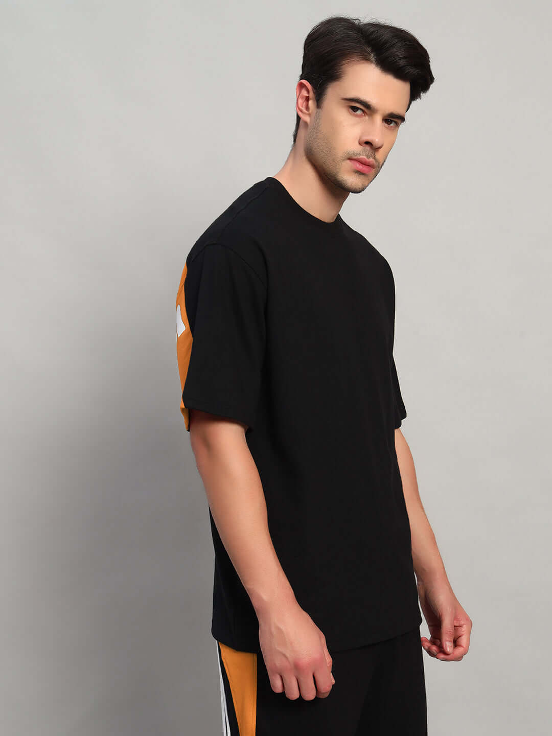 Model wearing TITAN OVER-SIZED T-SHIRT BLACK-ORANGE made of premium heavy gauge fabric, 97% cotton French terry, 3% elastane.