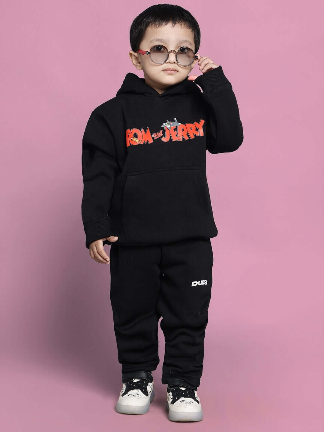 Child wearing black Tom & Jerry co-ord set with hoodie and pants in playful pose, suitable for boys and girls.
