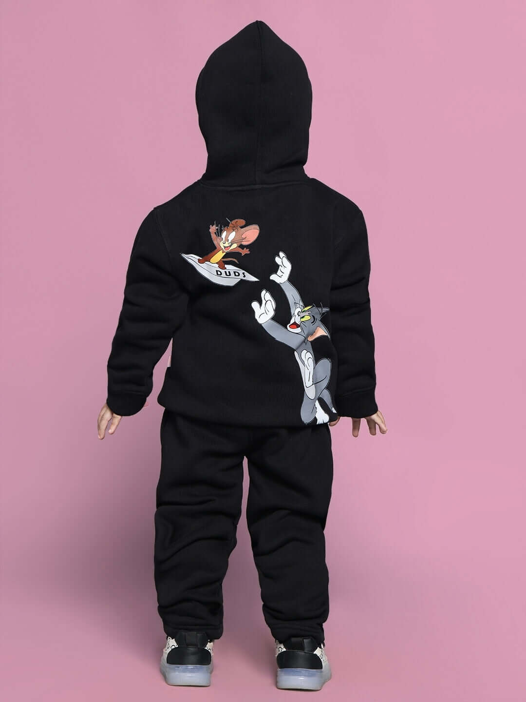 Child wearing TOM AND JERRY OVERSIZED FLEECE CO-ORD FOR BOYS GIRLS BLACK with colorful graphics, set against a pink background.