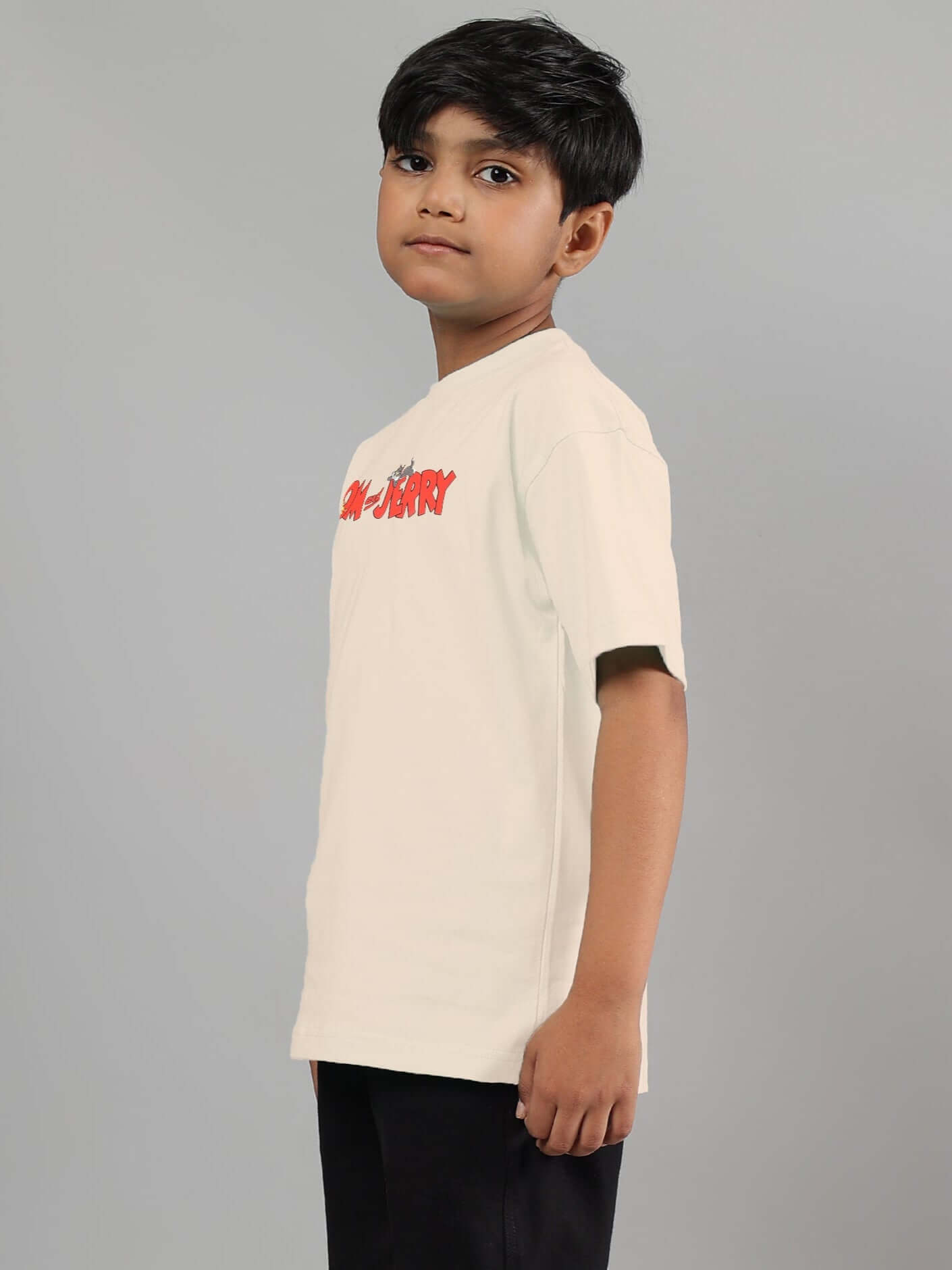 Boy wearing an off-white Tom & Jerry t-shirt designed for kids, with red logo print on the chest.