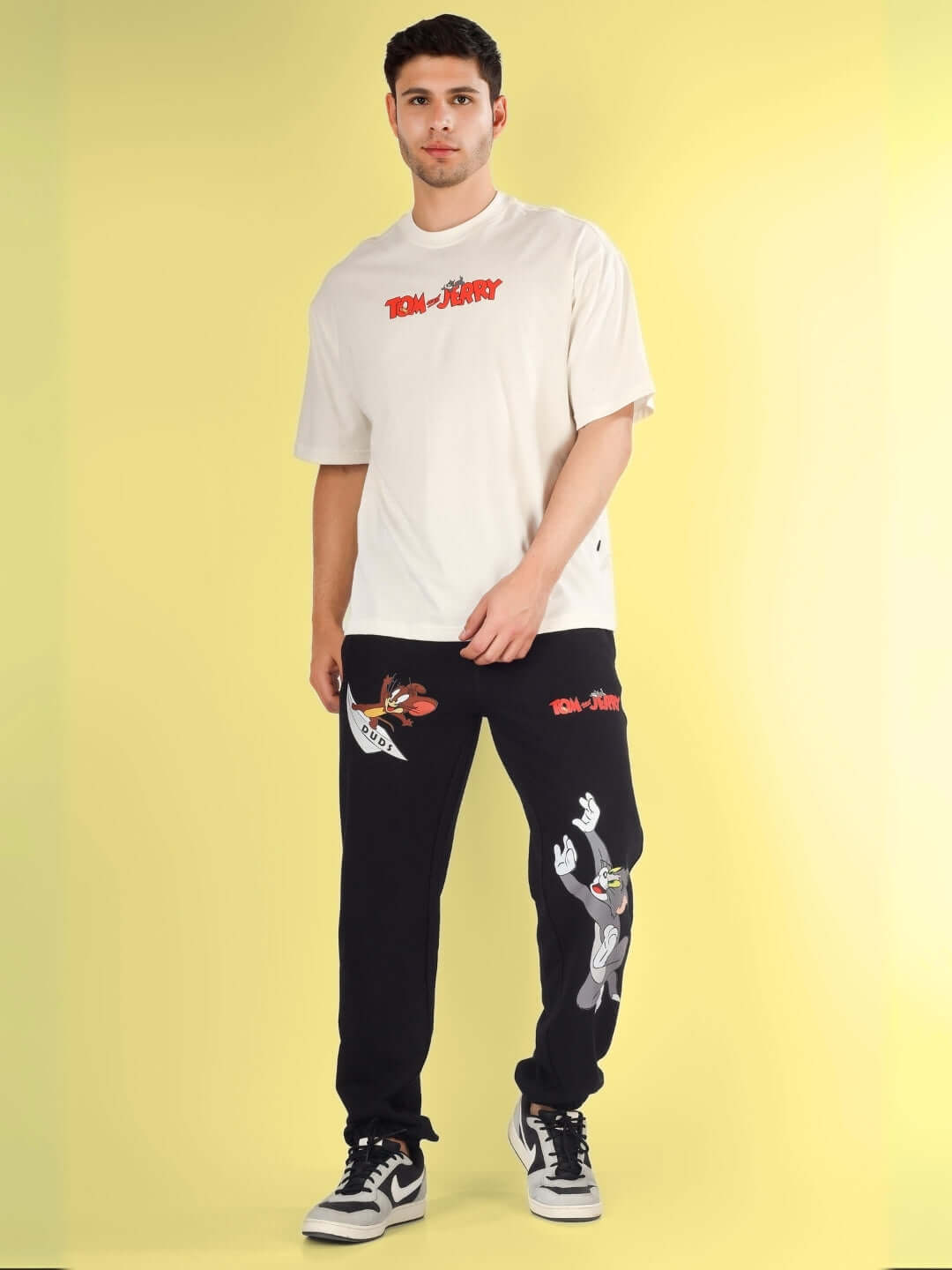 Model wearing Tom & Jerry relaxed black joggers with cartoon prints, customizable fit available, made-to-order by DUDS Tailors.